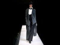 a woman in a black tuxedo walks down the runway